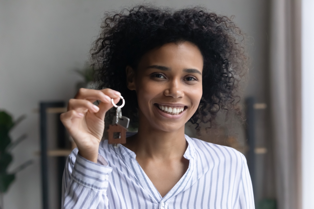 Biracial Woman holding up keys to her first house
©fizkes